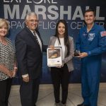 Woman,Sara Rengifo, receiving an award from astronauts Harrison Schmidt, U.S Senator and retired NASA astronaut, the most recent living person that has walked on the Moon; Rex Wilheim, NASA astronaut; and MSFC Center Director Jody Singer.
